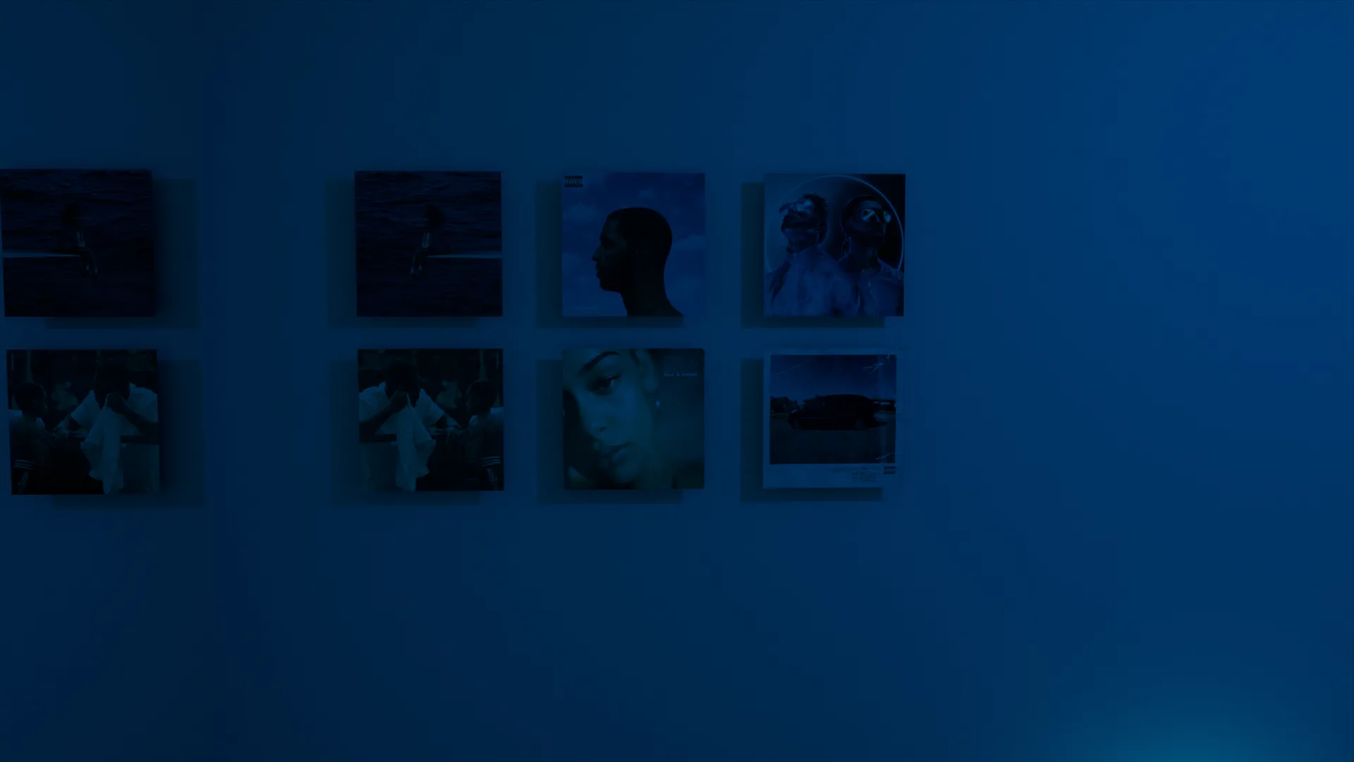 Le mur de cadres, photos et pochettes dans la pénombre bleue.